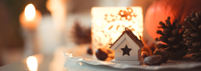 candles burning beside house shaped christmas orniments on a table - Holiday air quality, indoor air quality, toxic air, respatory illness, sweta-meininger_via Unsplash - Bill Salvatore, Arizona Elite Properties 602-999-0952 - Arizona Real Estate