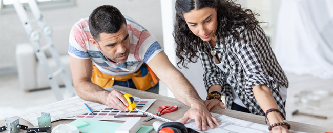 Man and woman using tape measure on table full of house plans and tools - Home Seller Updates, Upgrades, Home improvements, What updates should I do - Bill Salvatore, Your Valley Property Team - Arizona Elite Properties 602-999-0952