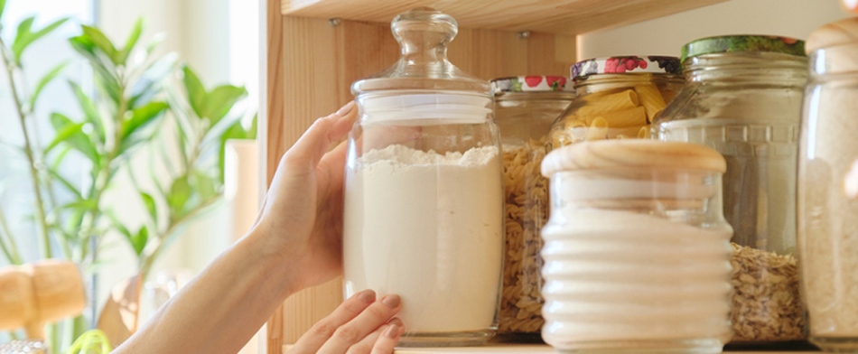 Hands placing a glass food canister on a kitchen shelf with other glass containers - photo via RIS Media - Bill Salvatore, Your Valley Property - Arizona Elite Properties 602-999-0952