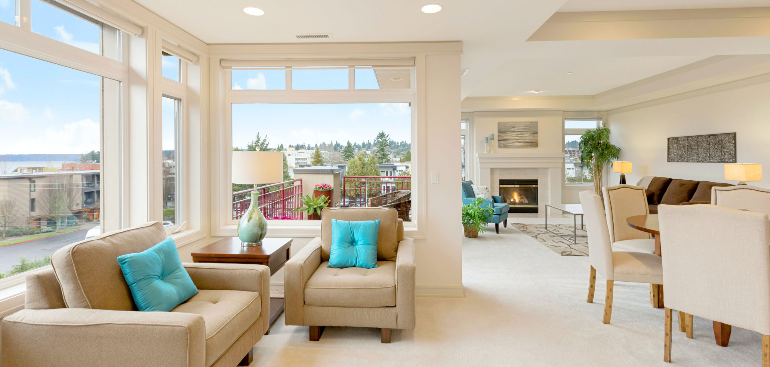 long room with wall of windows overlooking a city, white walls, white carpeting, fireplace, beige furniture - luxury home, luxury condo, townhom, francesca-tosolini-unsplash - Bill Salvatore, Your Valley Property Team - Arizona Elite Properties 602--999-0952