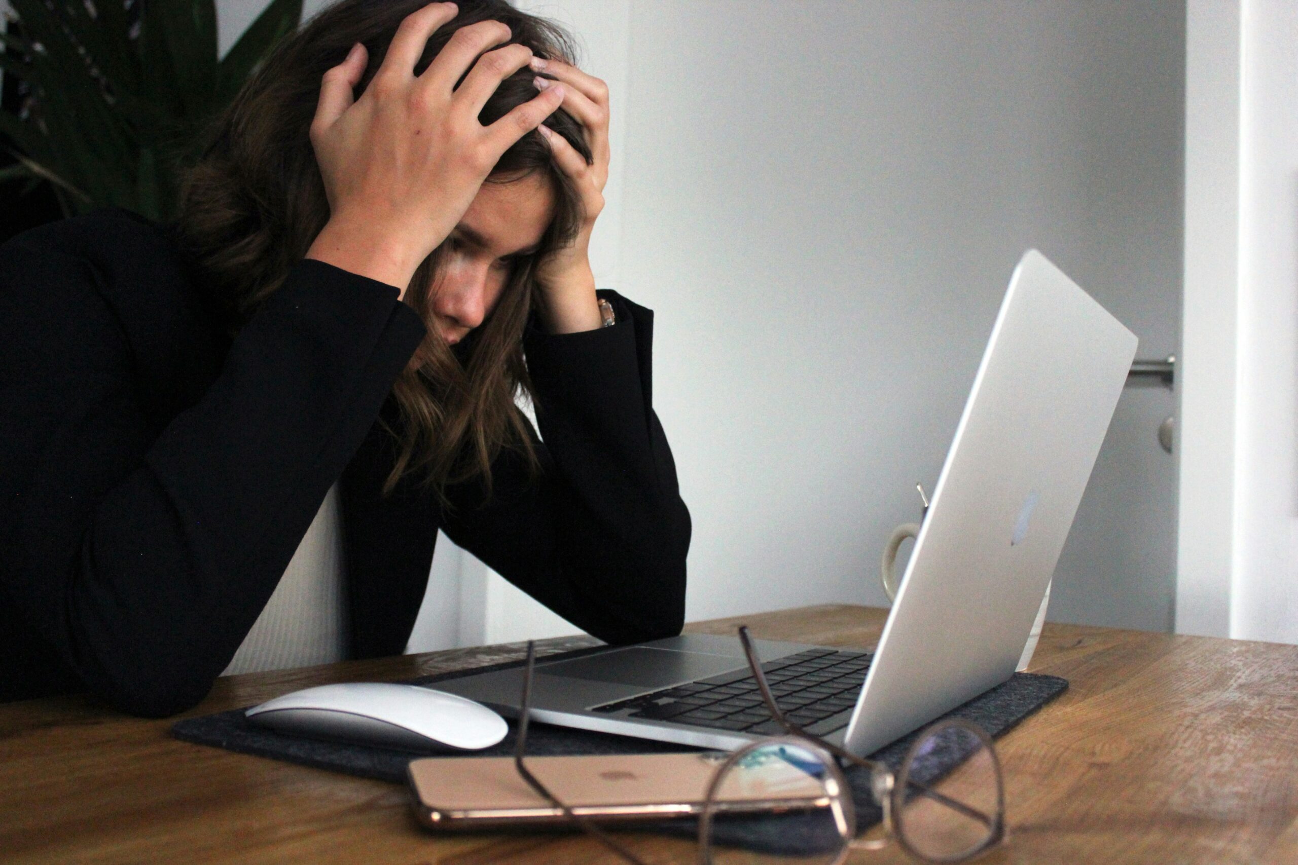 woman with head in hands looking at computer screen